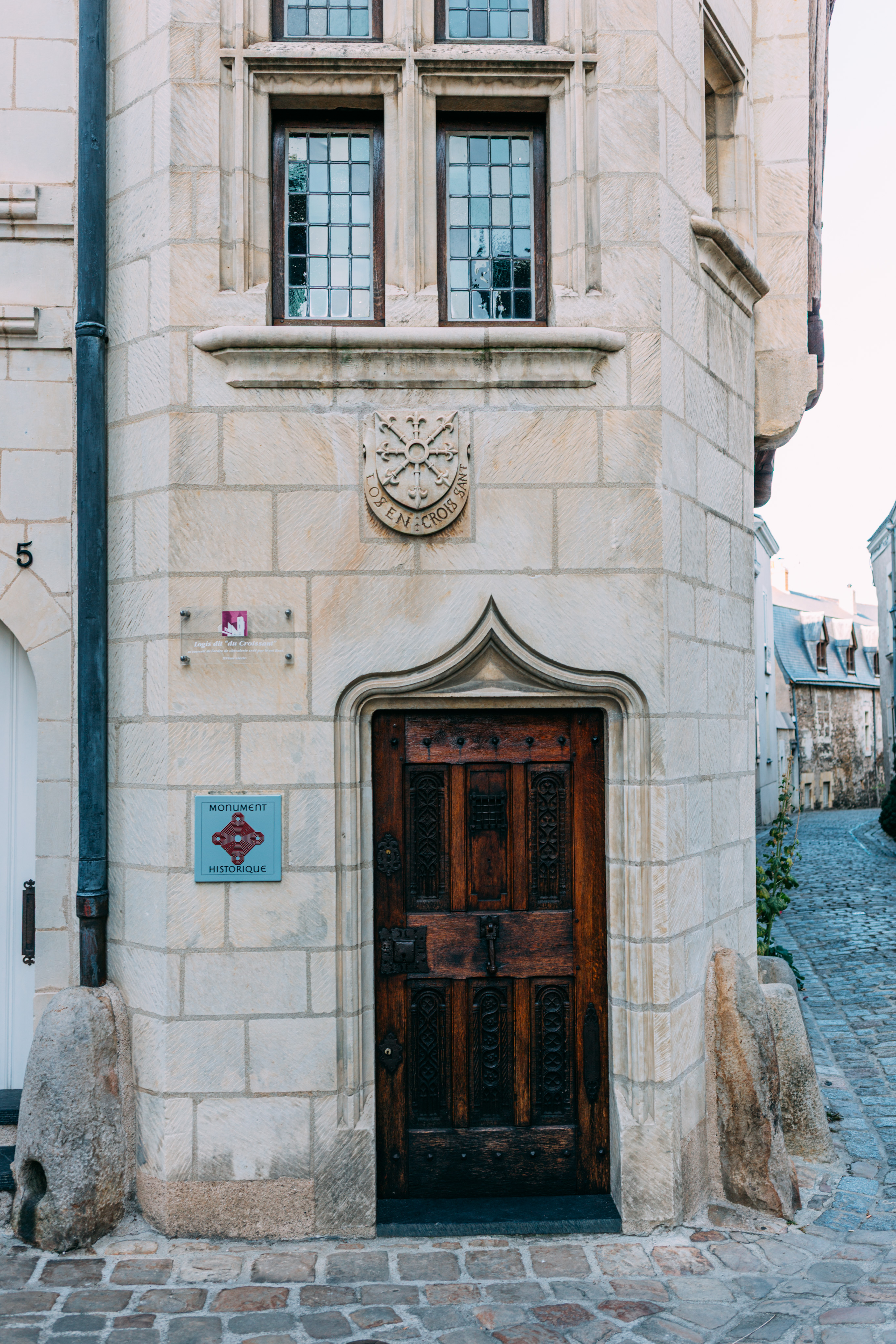 A wooden door in a stone building. There is a monument historique plaque posted to the left.